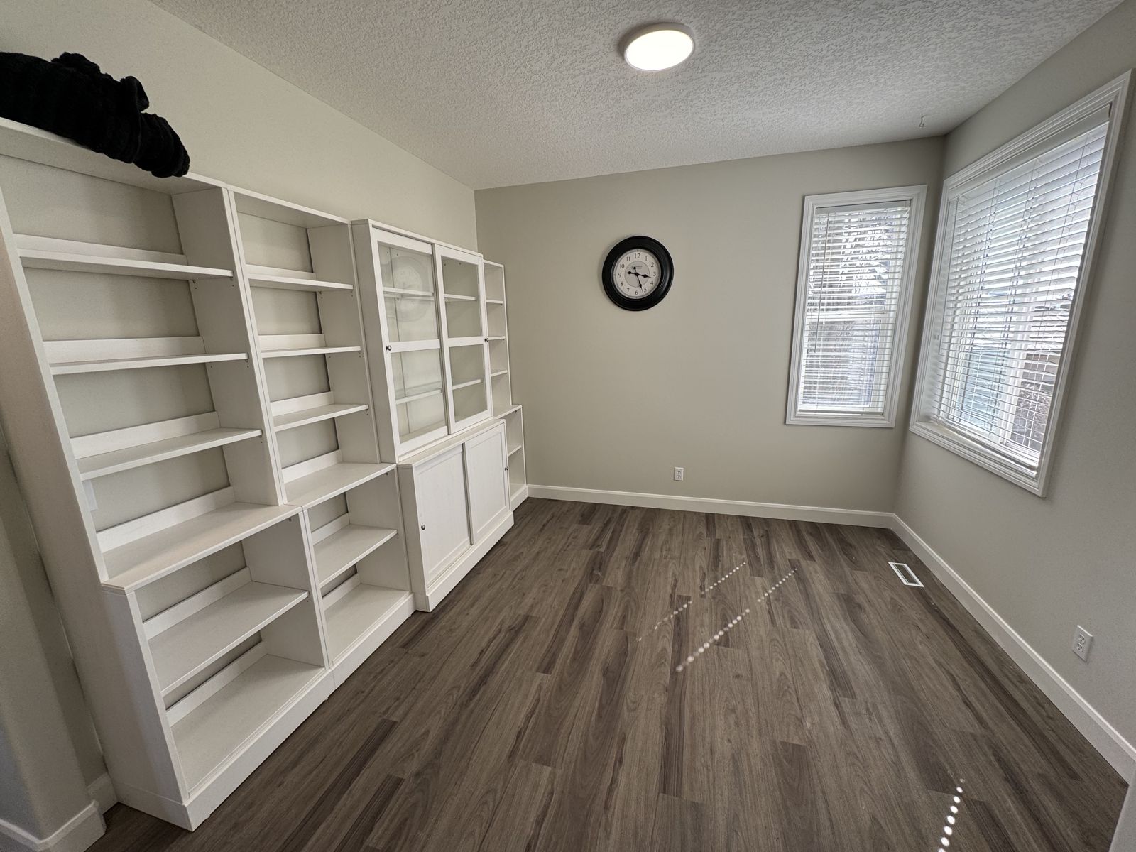 Room with white built-in shelving and cabinets along one wall