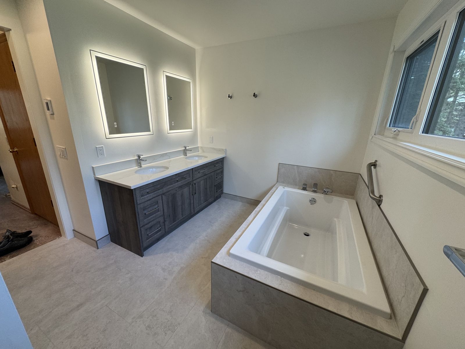 Renovated ensuite bathroom with soaker tub, tiled deck and backlit mirrors