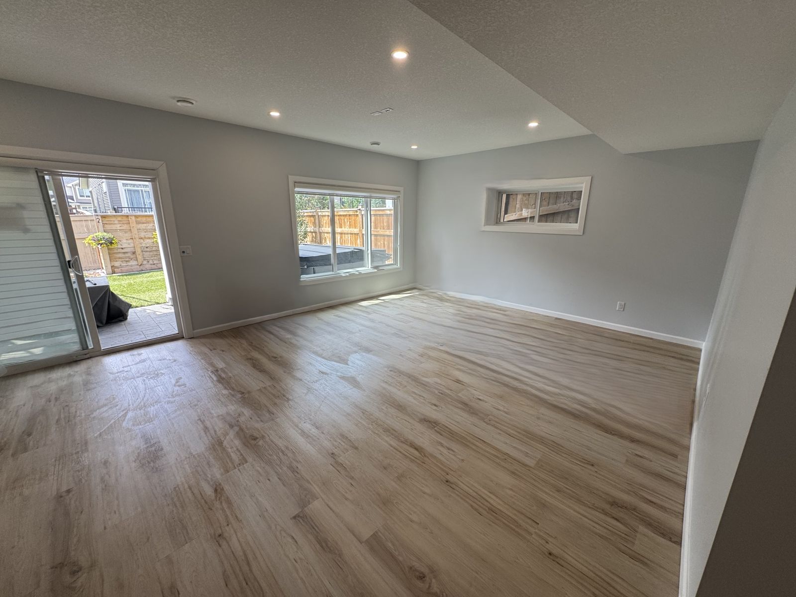 Bright finished walk-out basement rec room with light wood-look flooring